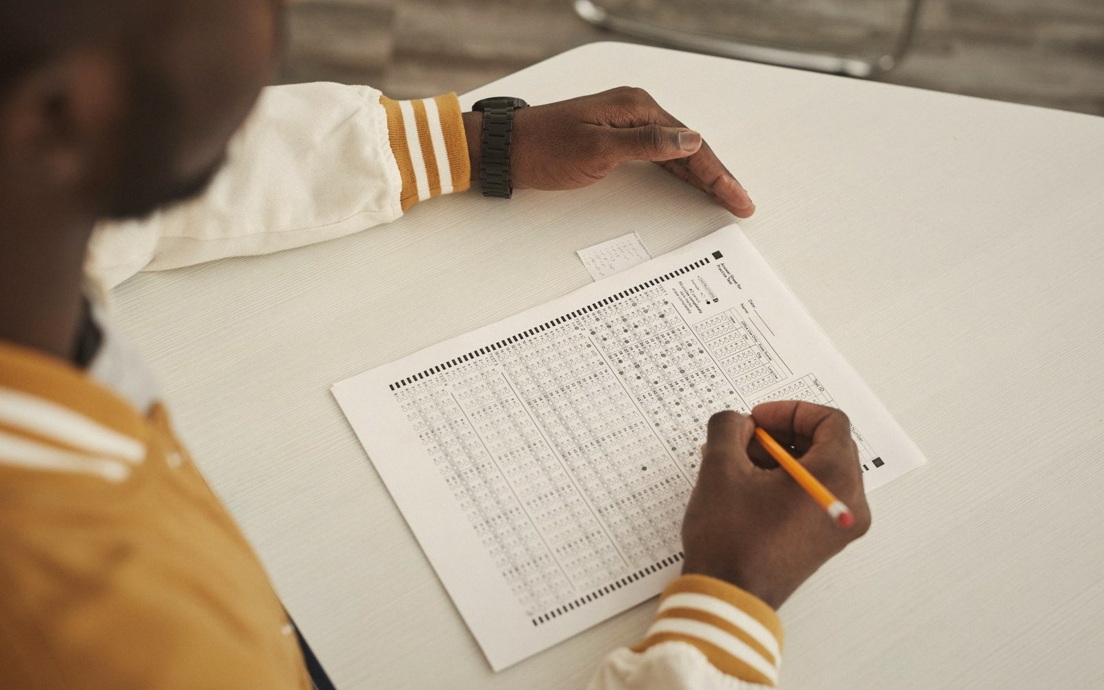 A stack of blank answer sheets and a tied biro on a table