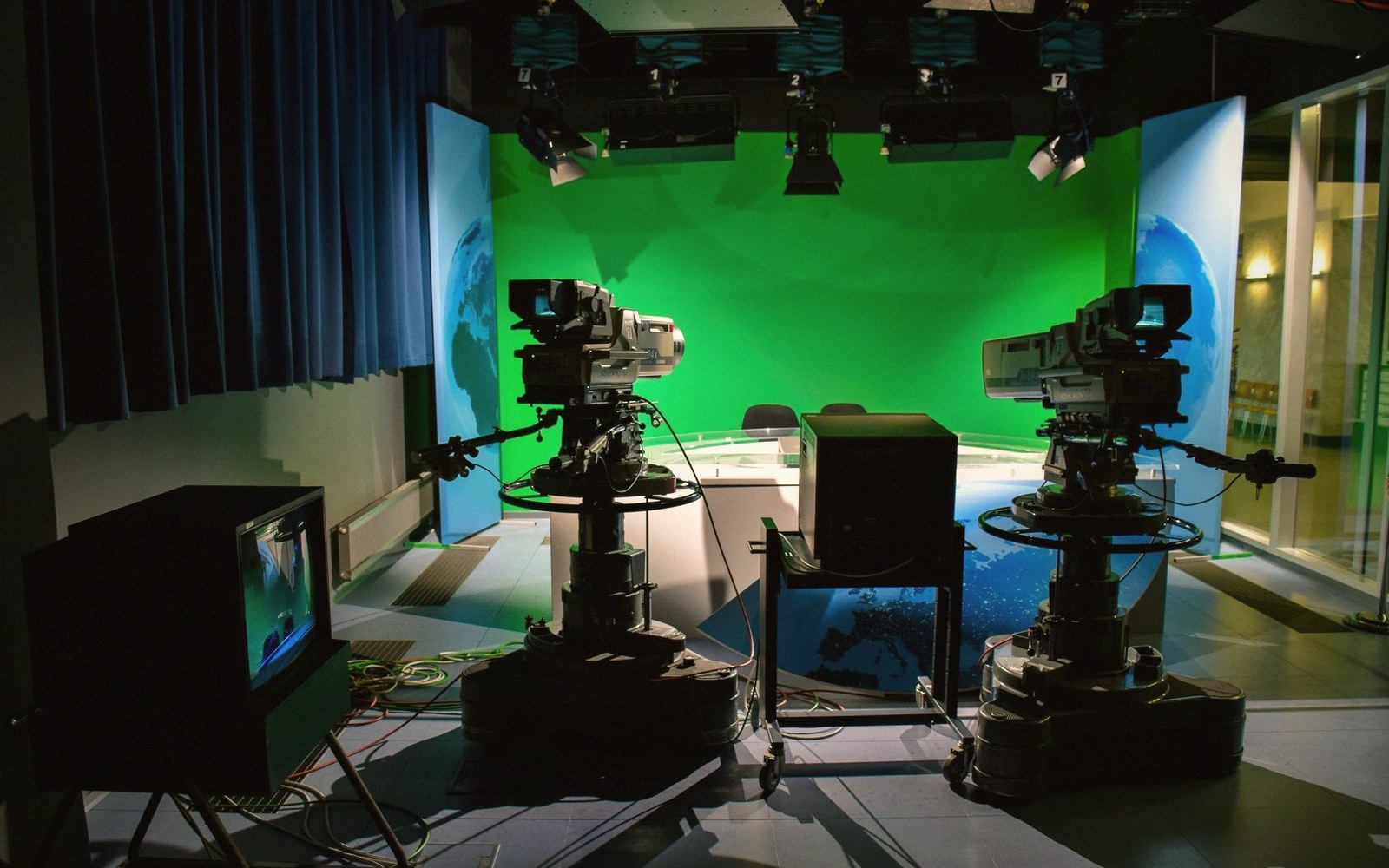Television studio with two broadcast cameras facing an empty green screen backdrop