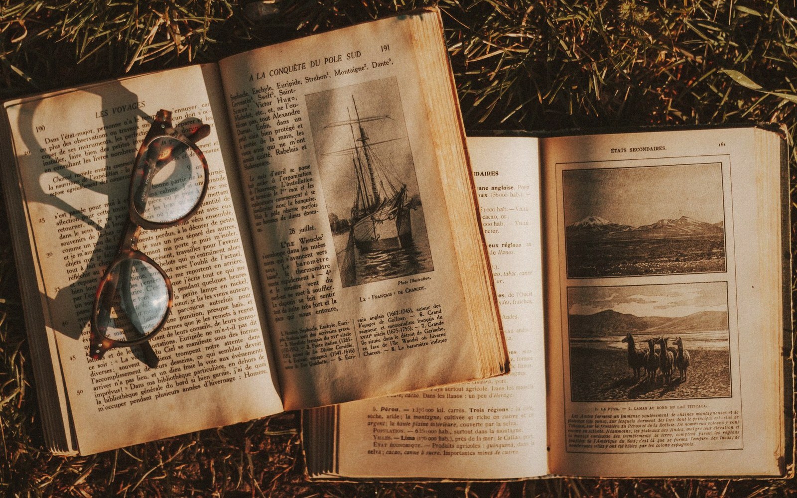 Eyeglasses resting on an open French book showing a ship illustration, beside another open book with photos
