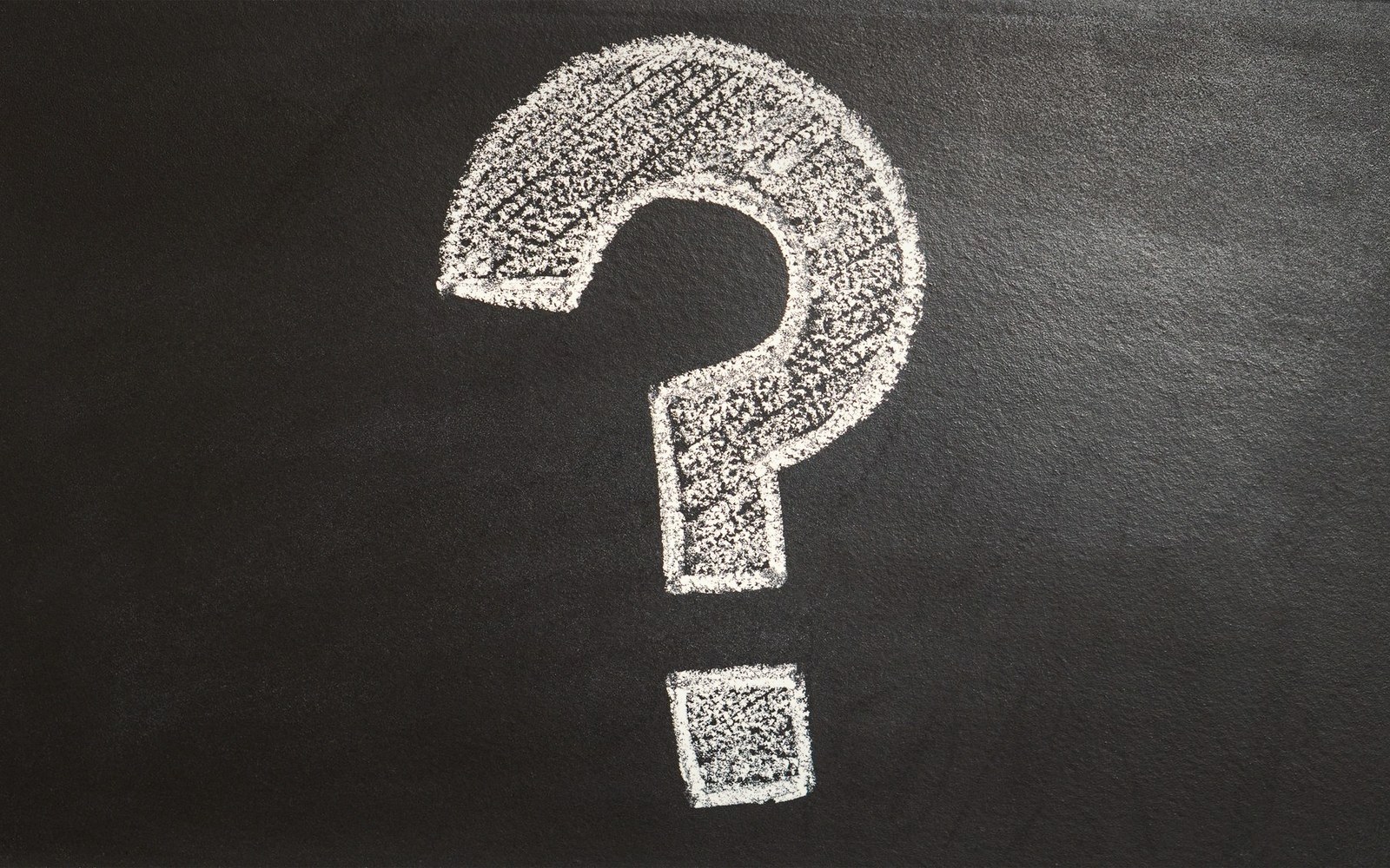 A large question mark drawn in white chalk on a blackboard